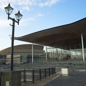 A stock image of the Senedd, a square grey building with an overhanging roof, and steps leading up to it.
