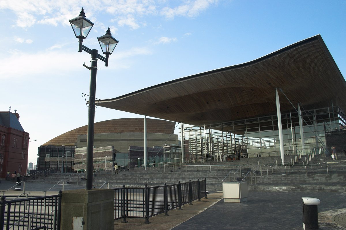 A stock image of the Senedd, a square grey building with an overhanging roof, and steps leading up to it.