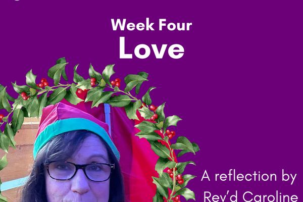 Rev'd Caroline is framed in a holly wreath. She is smiling, wearing black large framed glasses and a green and red elf hat. Above her the text reads Advent Four. Love. A reflection by Rev'd Caroline
