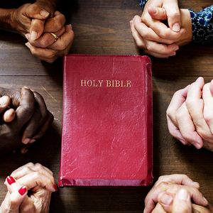 Bible and hands clasped