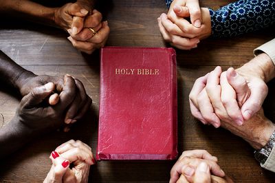 Bible and hands clasped