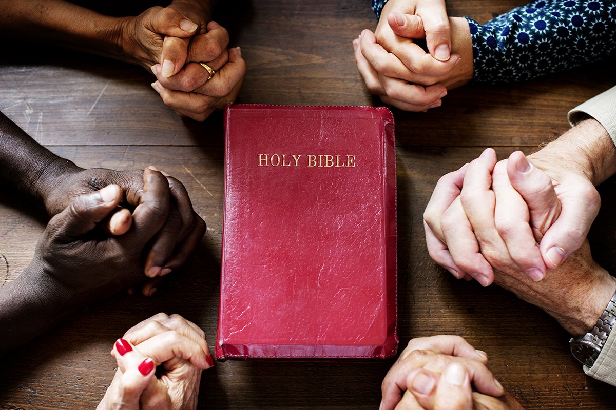 Bible and hands clasped