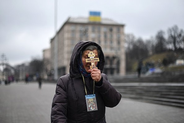 A religious woman holds a cross as she prays on Independence square in Kyiv. (Photo by DANIEL LEAL/AFP via Getty Images)