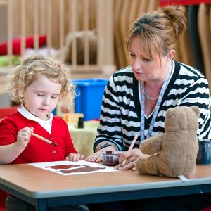 A teacher and child creating painting