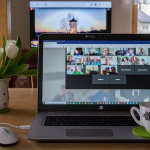 A laptop with a Zoom video call open and a cup of coffee